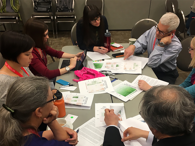 Practitioners participate in a group exercise around a table during a training session on using climate projections.