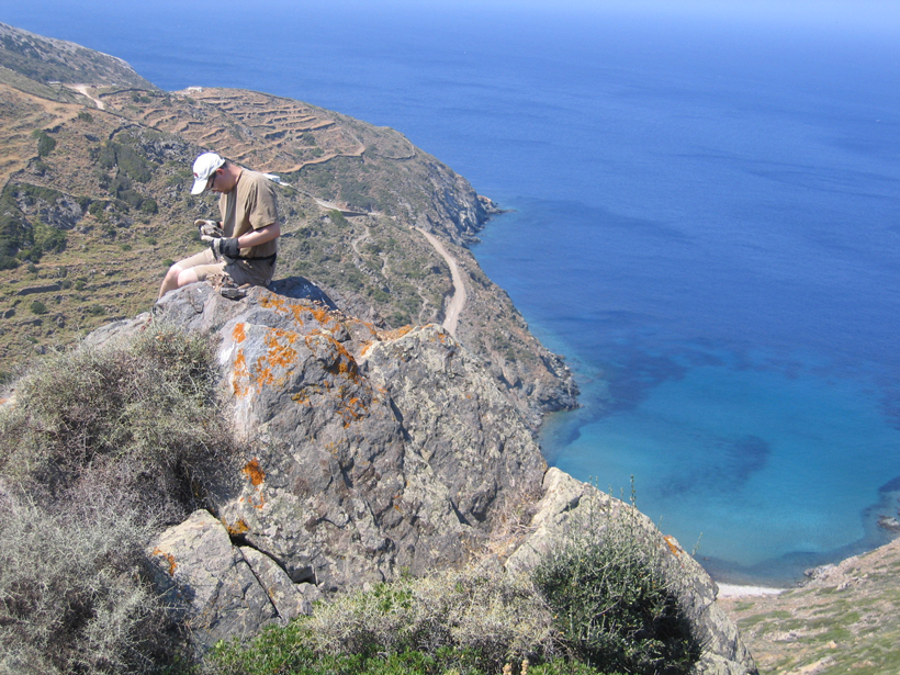 Ethan Baxter examining garnet samples on an island cliff in Sifnos, Greece