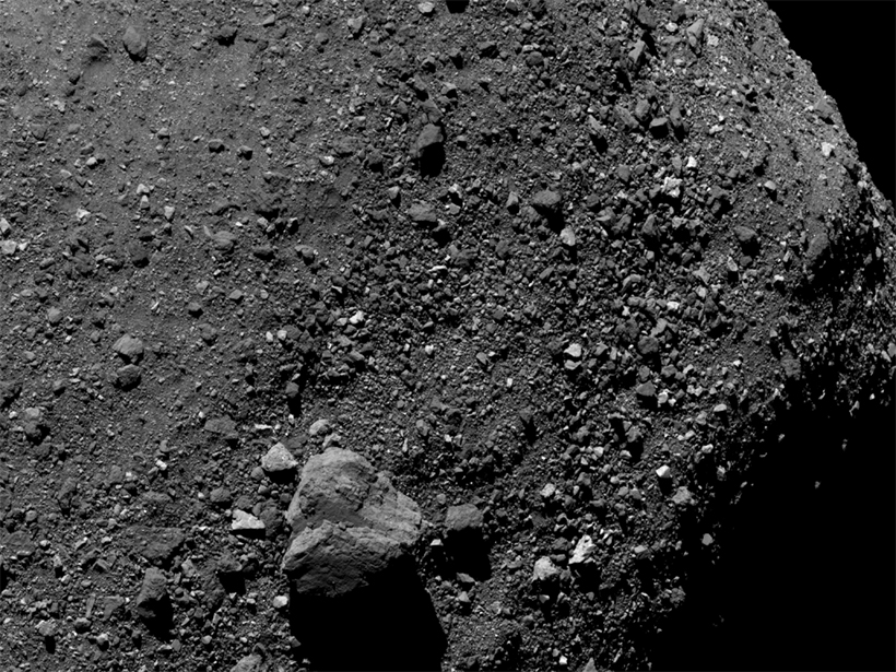 Grayscale image of asteroid Bennu with large bolder