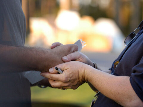 A Federal Emergency Management Agency worker holds a disaster victim’s hand.