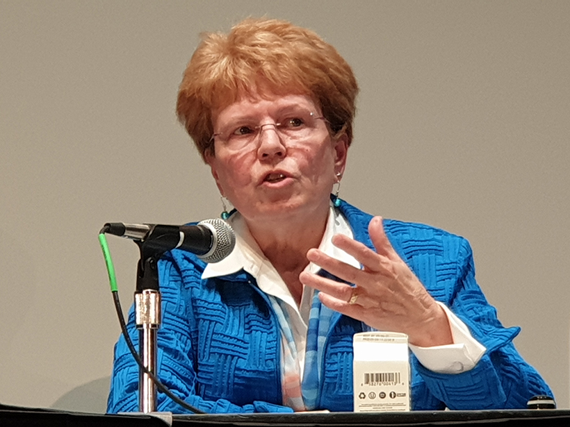 Former NOAA chief Jane Lubchenco speaks into a microphone while seated at a table.