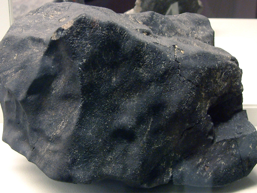 a black meteorite sitting on a white table