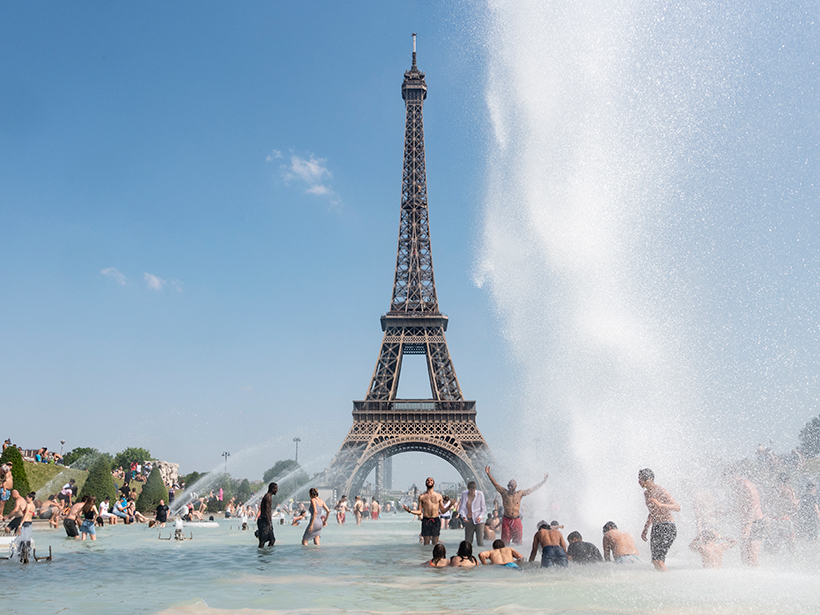 People play in a fountain overlooking the Eiffel Tower in Paris during a heat wave.
