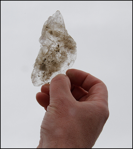 Hand of a white man holds a dirty ice shard. Hand of a white man holds a dirty ice shard.