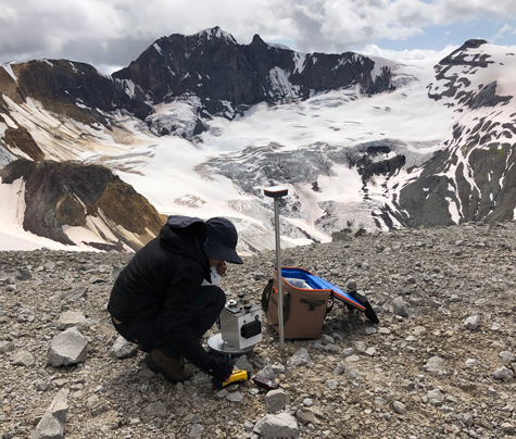 A researcher sets up a gravimeter near a mountain glacier. A researcher sets up a gravimeter near a mountain glacier.