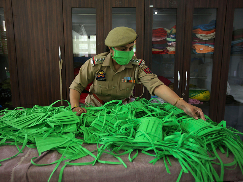 An officer checks the quality as police personnel make face masks and personal protective gear amid COVID-19 outbreak in Jammu, India.