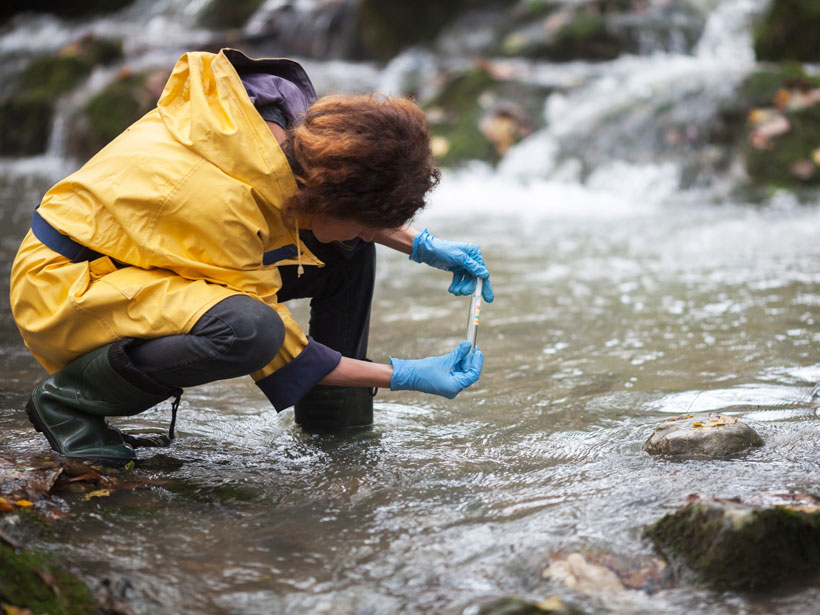 Scientist takes a water sample at a river