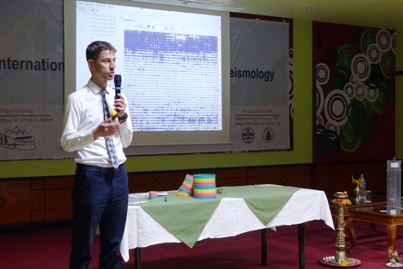 Seismologist György Hetényi lectures in front of a seismometer reading