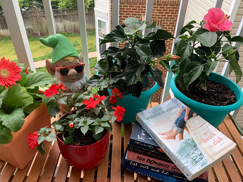Stack of books surrounded by potted plants and a garden gnome
