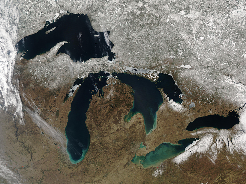 A springtime satellite view of the five Great Lakes shows the snowline roughly following the U.S.–Canadian border.
