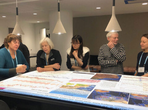 Scientists stand around a table looking at a research poster