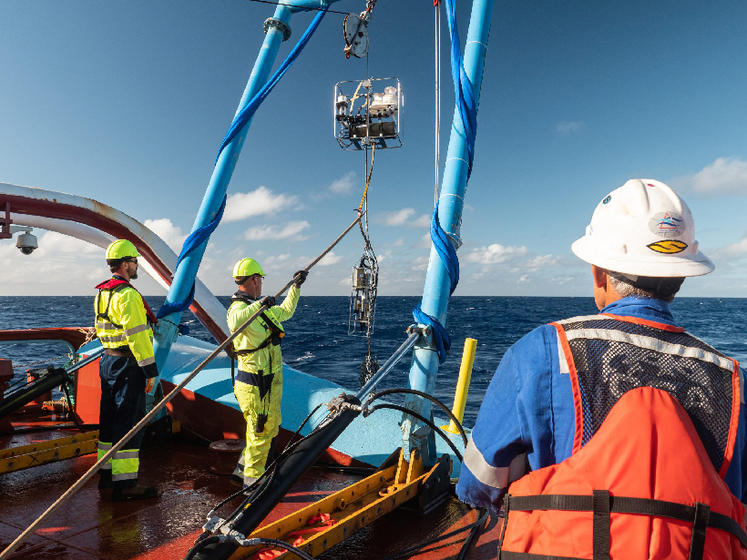 Men on the deck of a research vessel collect samples from the Great Pacific Garbage Patch.