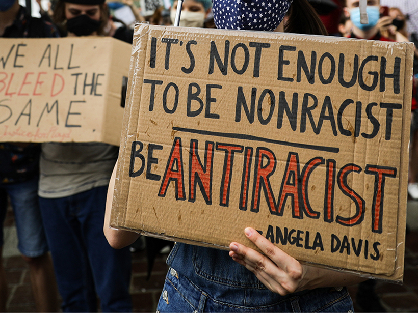 Handwritten cardboard signs from a Black Lives Matter protest in Poland, centered on a quote from Angela Davis about antiracism.
