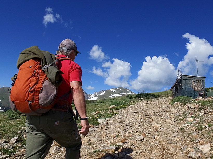 A man backpacks up a rocky trail to an air-sampling station