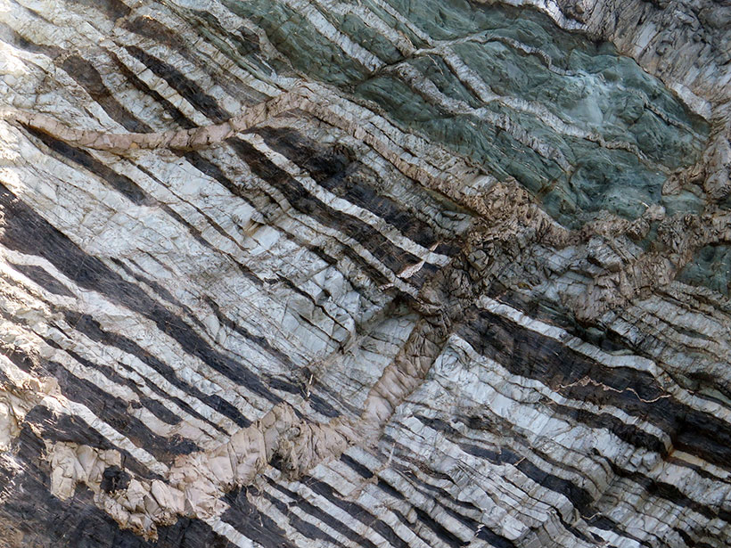 An outcrop of the Franciscan complex on Santa Catalina Island in California, with white quartz veins crosscut by pale beige silicic magmatic dikes