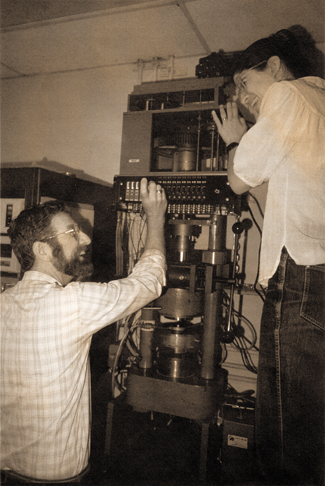 Photo from the 1990s showing a man and woman with a large instrument Photo from the 1990s showing a man and woman with a large instrument