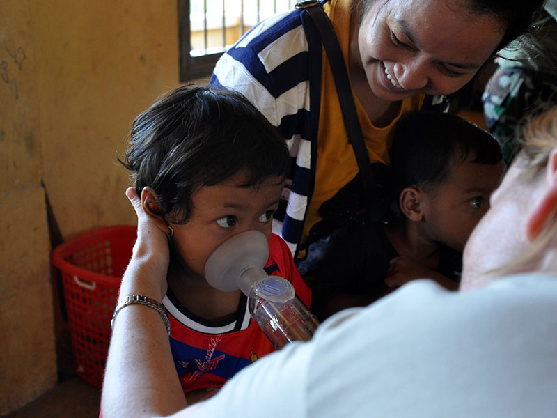 A young girl in Cambodia practices inhaling asthma medication
