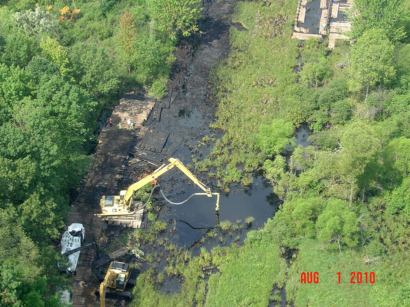 An aerial shot of a crew cleaning up an oil spill in a river