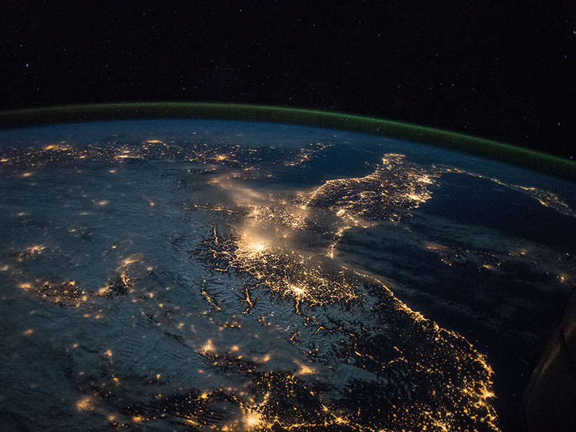 A thin layer of green aurorae glows on the horizon above Earth in a photo taken from the International Space Station.
