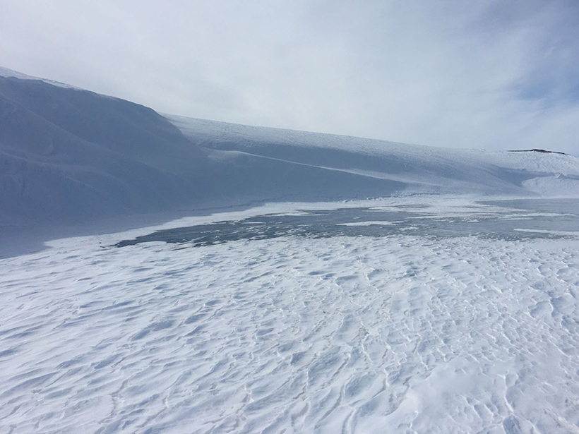 Aerial view of snowdrifts at a lake in the northern foothills of the Brooks Range in Alaska