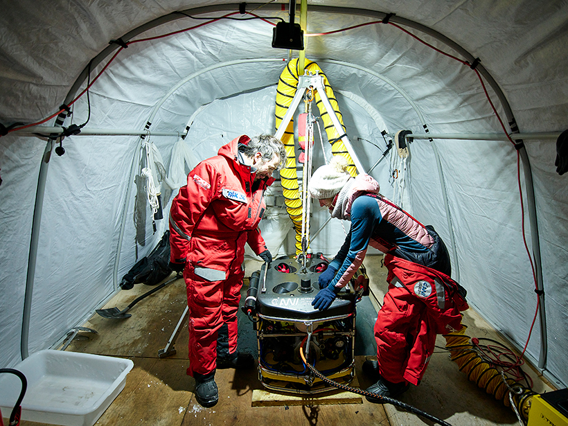 Scientists stand in a tend with the ROV