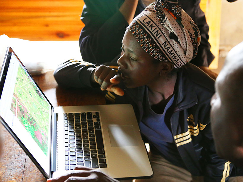 A man and woman study the screen of a laptop.