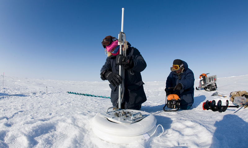 Two scientists measure snow and ice in the Arctic Two scientists measure snow and ice in the Arctic