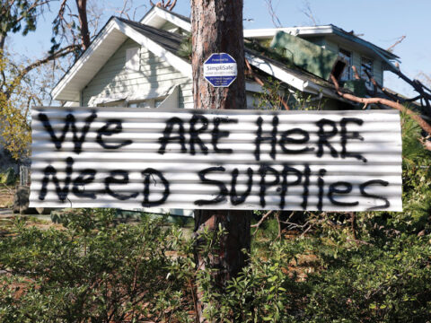 A sign hangs on a tree in front of a house damaged by Hurricane Michael in Panama City, Fla., in 2018.