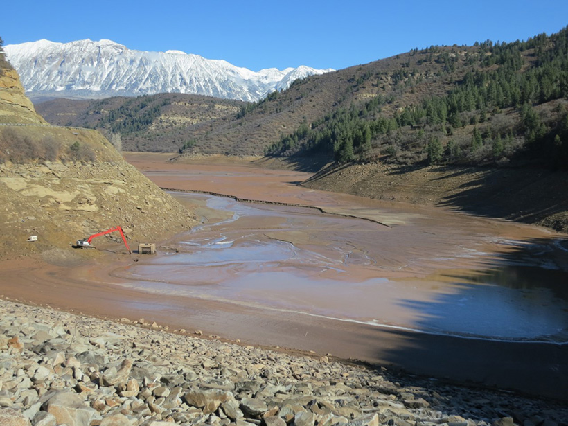 An excavator sits in the sediment-filled Paonia Reservoir in the Colorado mountains