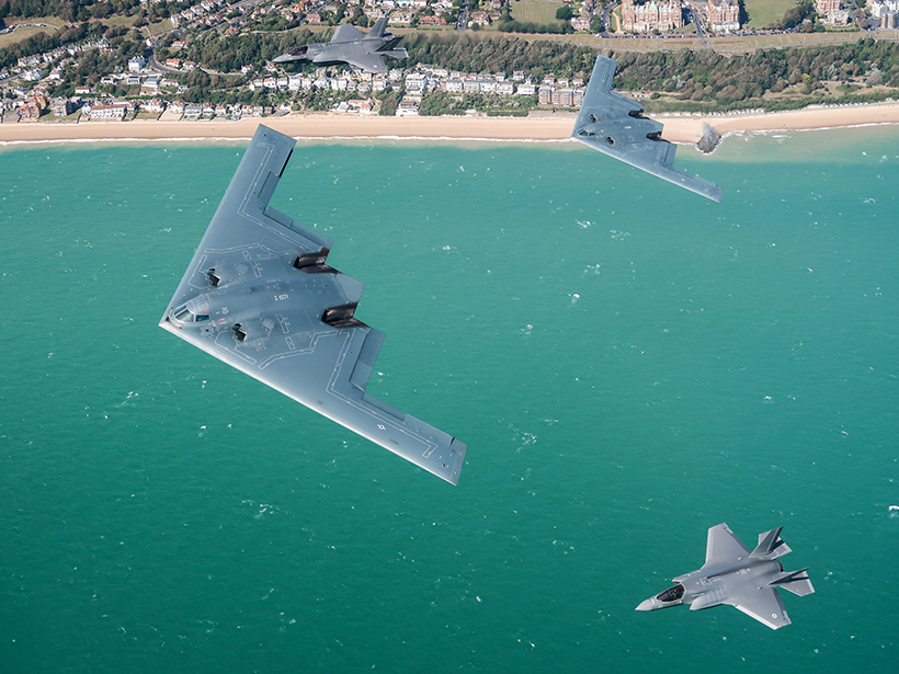 Two U.S. Air Force planes fly over the ocean.