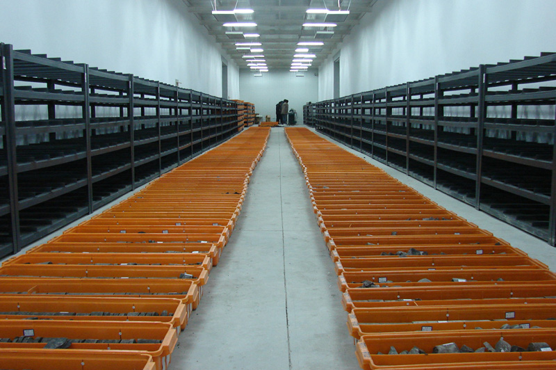 Containers of sediment core line the floor of a long storage room