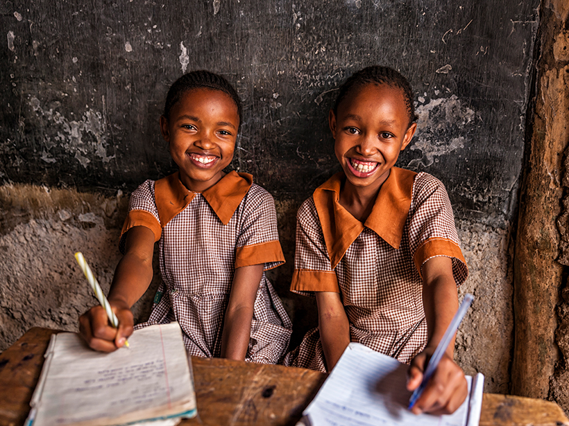 Dos radiantes estudiantes sentadas en un escritorio en Nairobi, Kenia.