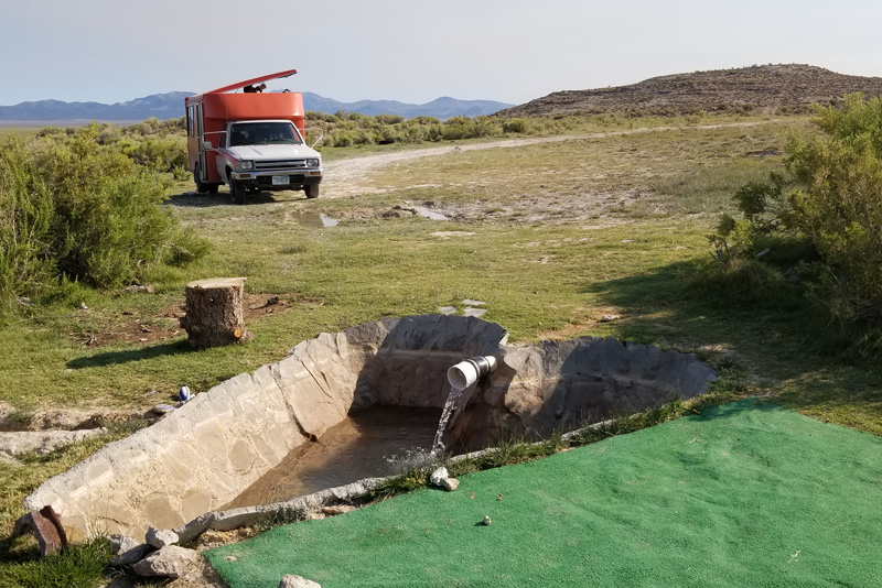 Water flows out of a white pipe into a heart-shaped concrete hot tub in the Nevada desert. Water flows out of a white pipe into a heart-shaped concrete hot tub in the Nevada desert.