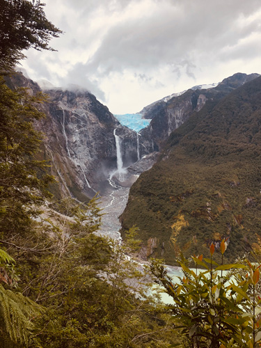 Waterfalls pouring from a distant glacier run down a valley toward a mountain lake. Waterfalls pouring from a distant glacier run down a valley toward a mountain lake.