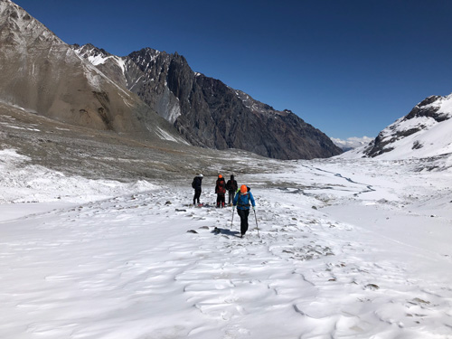 Four people stand on snowy ground in a high mountain valley. Four people stand on snowy ground in a high mountain valley.
