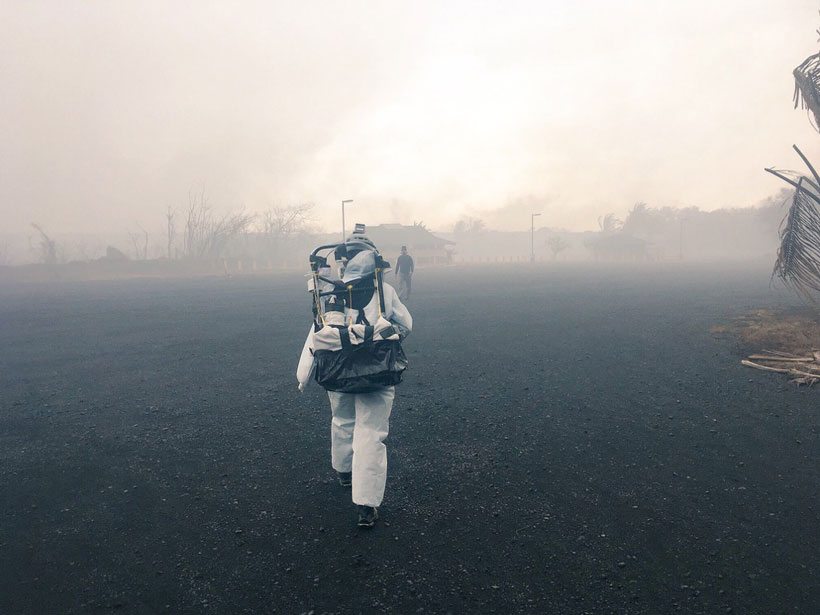 A researcher wearing a protective suit walking toward a laze plume.