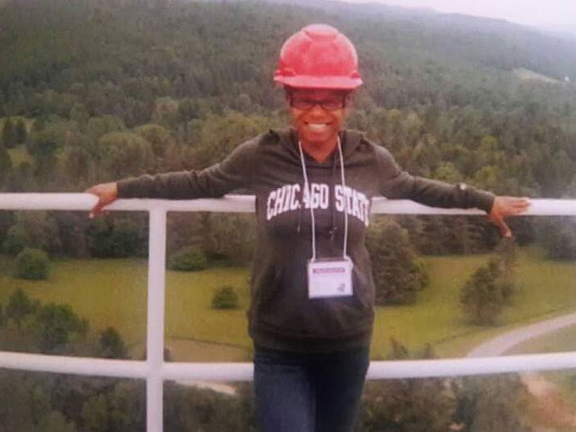 Ashley Walker stands against a railing on a platform overlooking the wooded mountains surrounding the Green Bank Telescope in West Virginia.