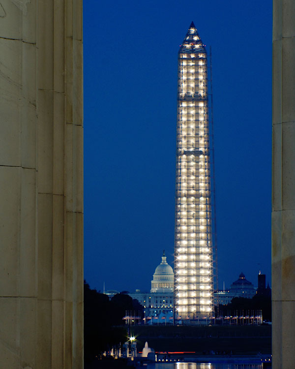 A nighttime view of the Washington Monument surrounded by scaffolding.