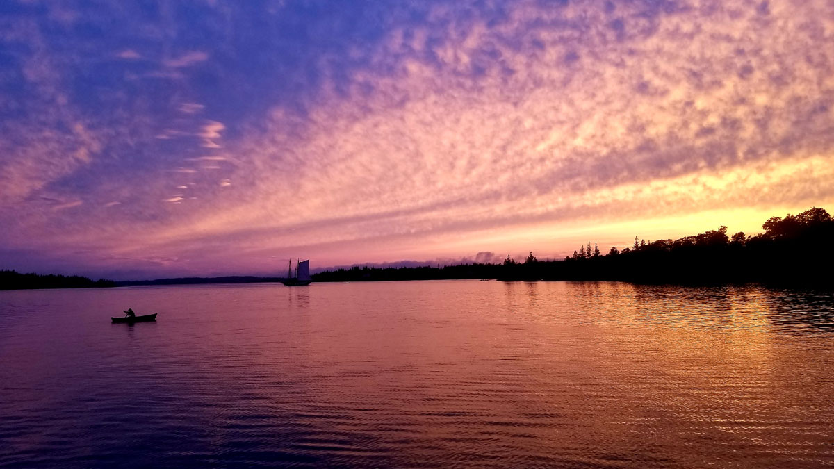 Sunset on the Maine coast from the deck of the schooner Victory Chimes, with one of the ship’s small dories and another sailboat on the horizon.