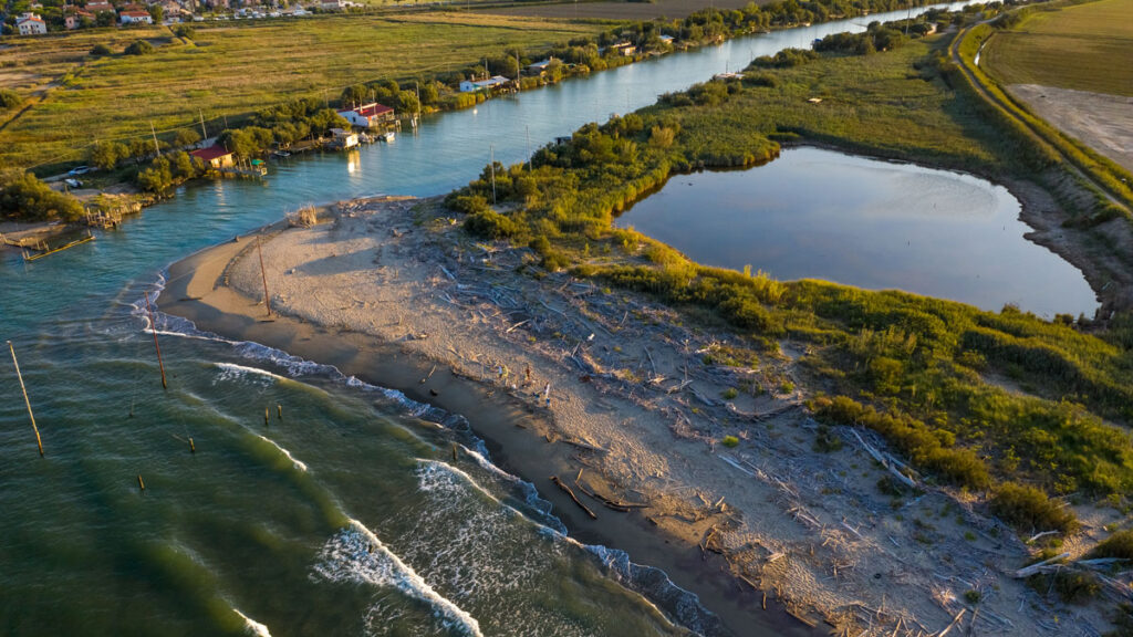 A grassy landscape next to a river and the ocean.
