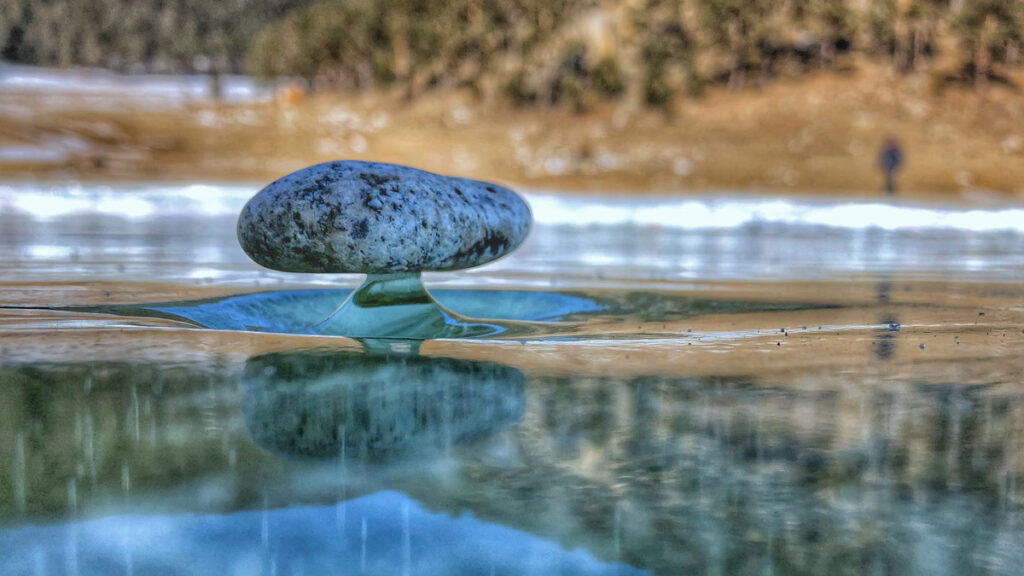 A rock balances on a thin leg of ice.
