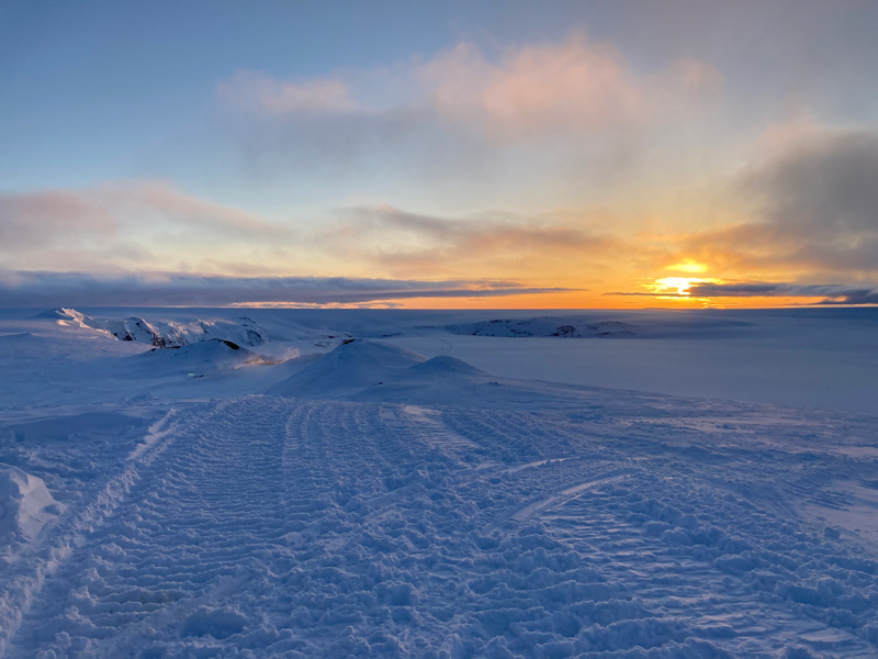 The Sun sets behind a snow-covered volcanic caldera.