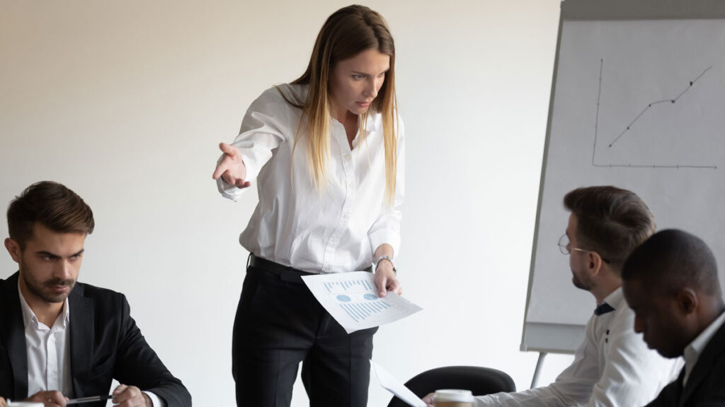 At group meeting businesspeople gathered in boardroom witness a conflict between a boss and an employee.