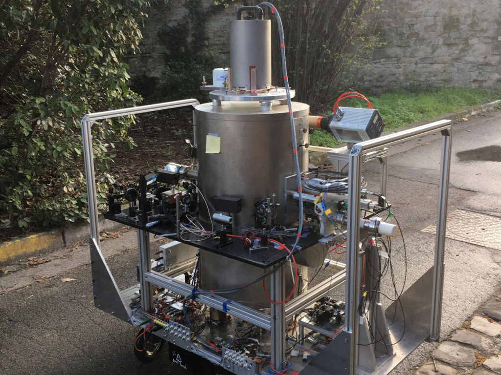 An absolute gravimeter sits on a cart with wheels on a sidewalk outside.