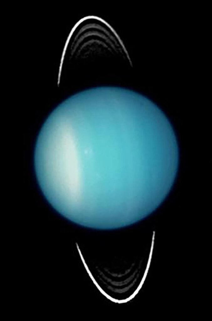 Uranus is seen in blueish green with vertical streaks of color on a black background. Four arcs of white rings are visible above and below the planet.