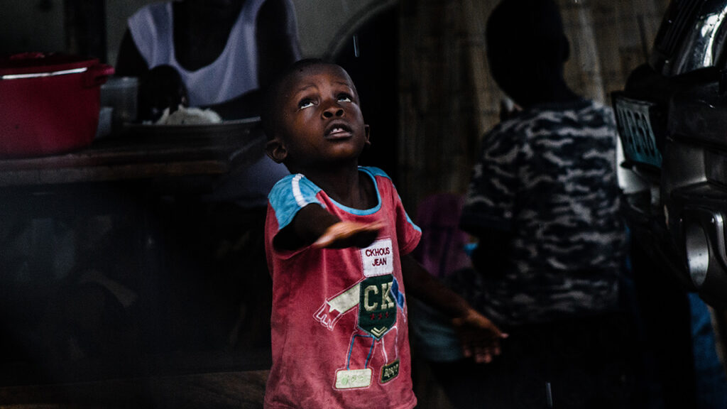 A child holds his hand out to the rain.