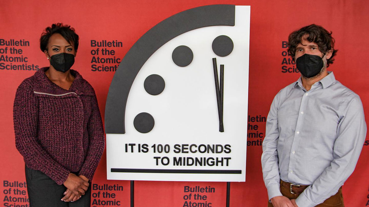 Photograph of two people standing next to the Doomsday Clock