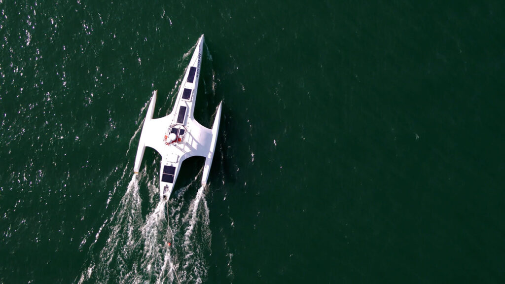 A white seacraft moves through deep green water