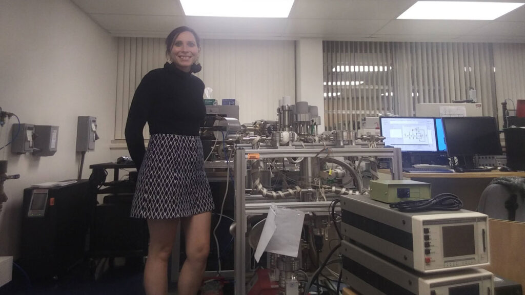 A geoscientist smiles in front of the new IsotopX NGX multi-collector NGX noble has mass spectrometer and extraction line at the University of Florida.