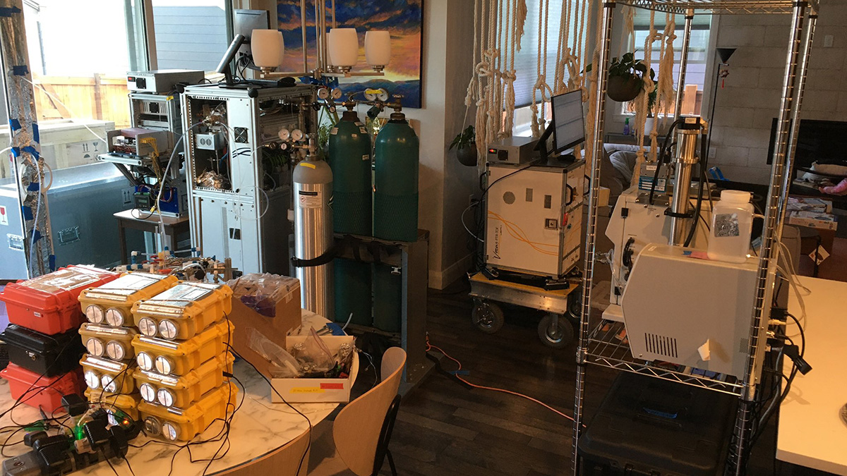 A room in a home filled with atmospheric research equipment, including three gas cylinders that are connected to a mass spectrometer.